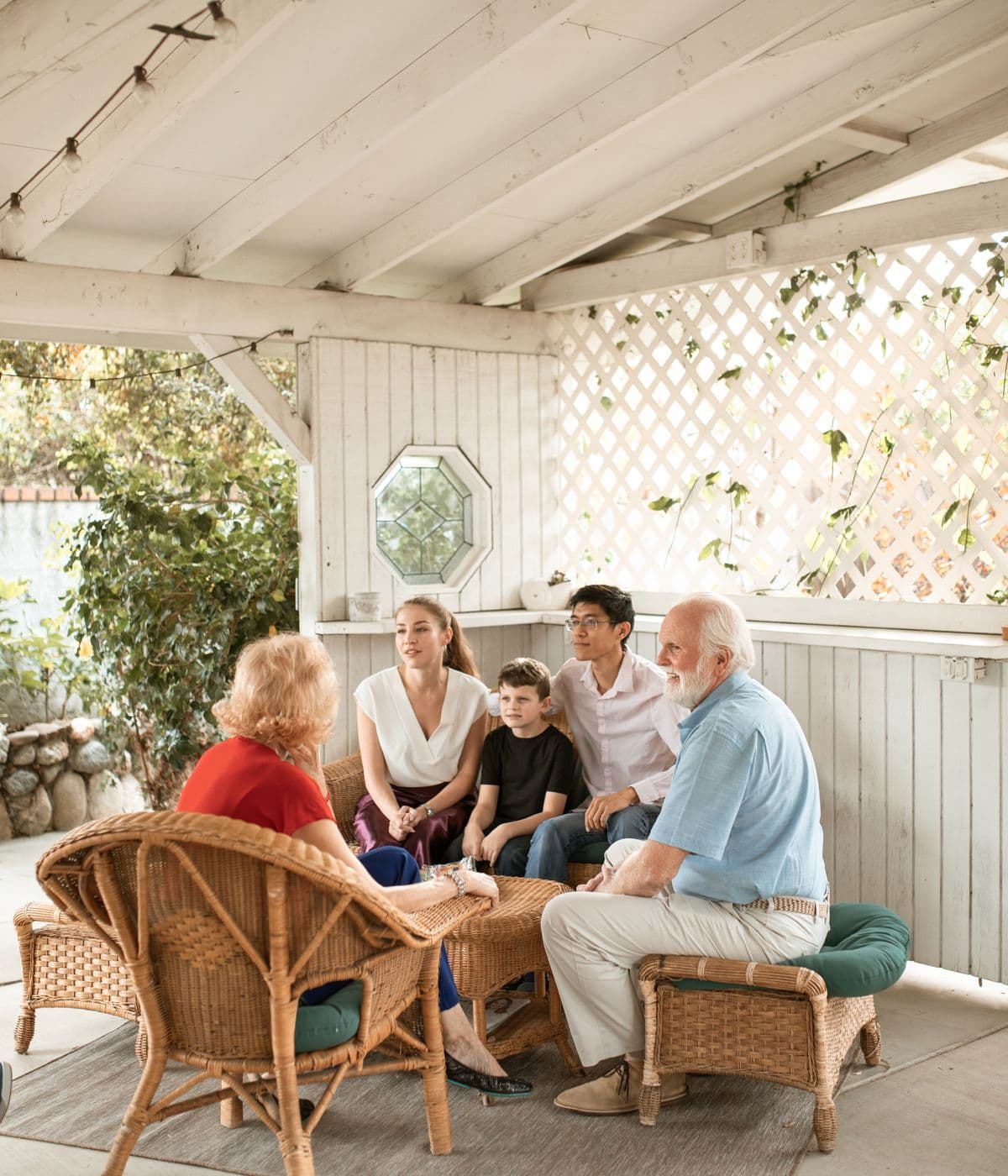 Multigenerational family sitting together in conversation on a covered porch